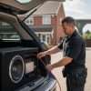 Installer working on a car audio system in a vehicle boot